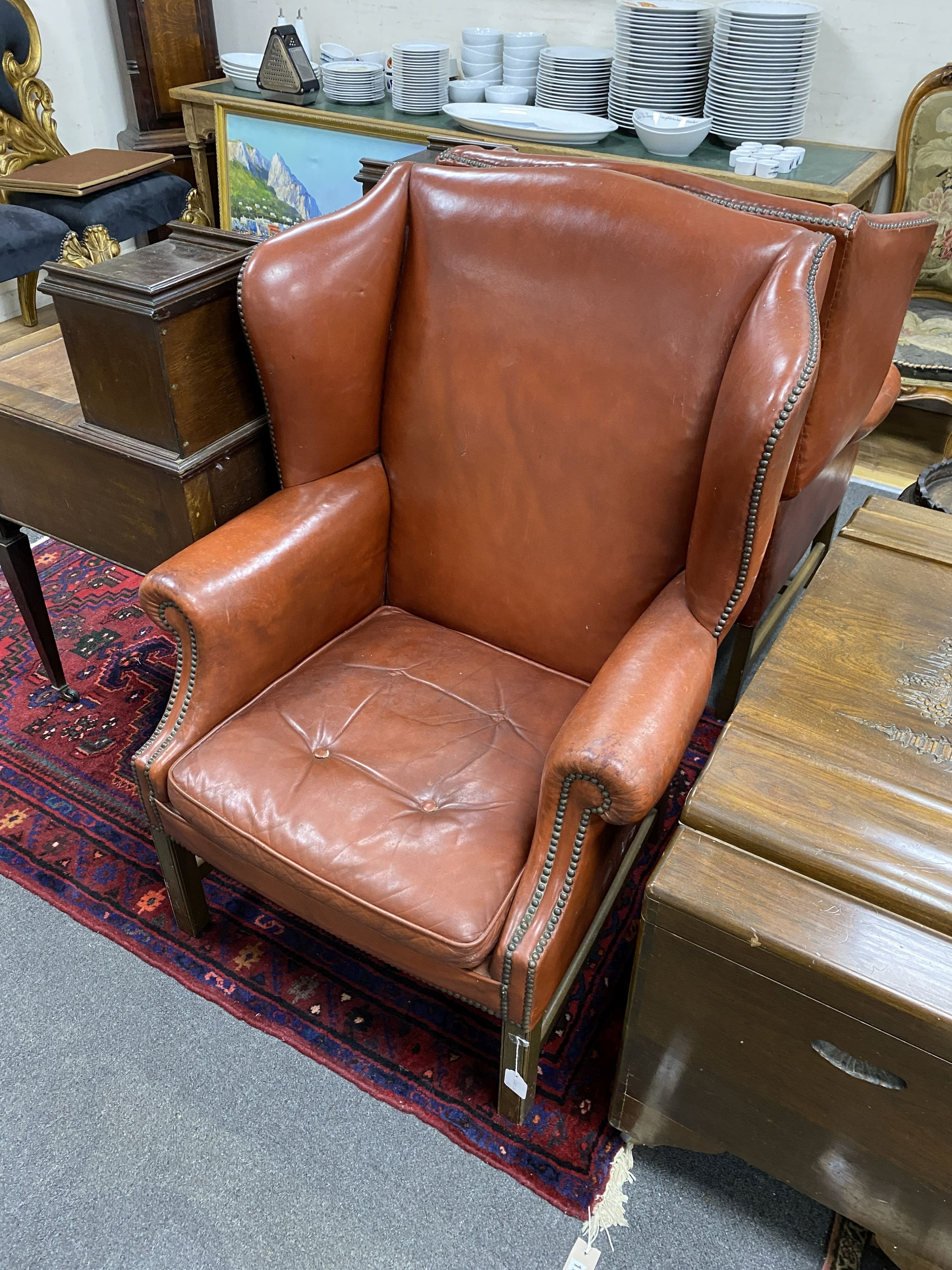 A pair of George III style studded red leather wingback armchairs, width 79cm